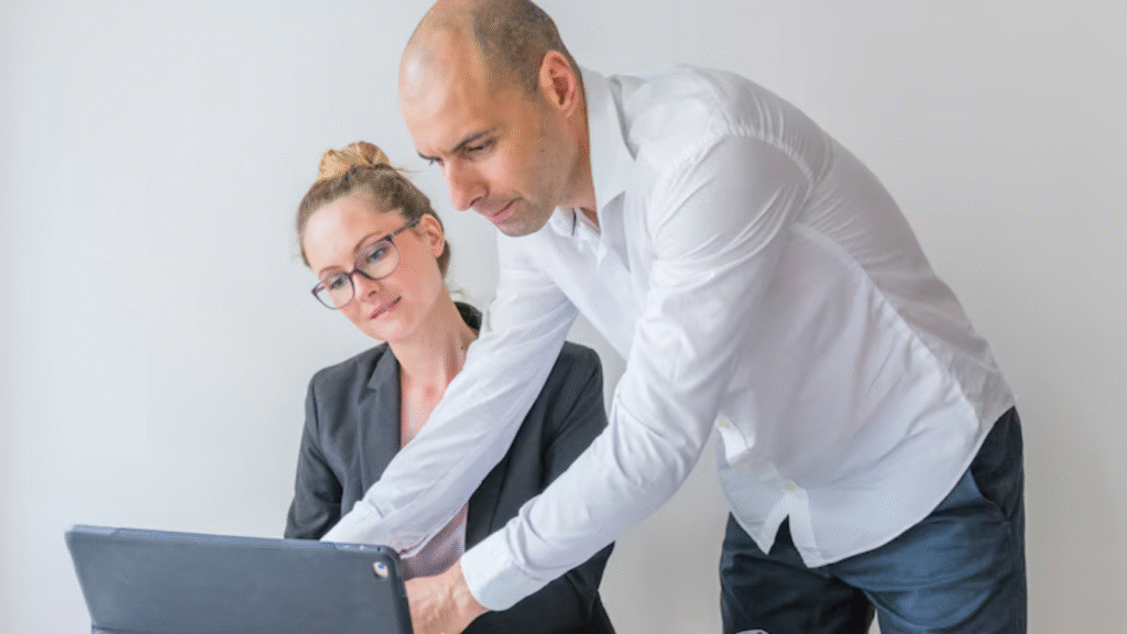 Two colleagues collaborating on a laptop in the office and working on MOHRE & GDRFA Clearances in Dubai.